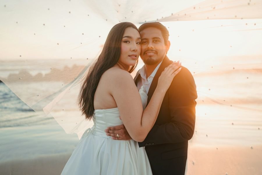 Bride and groom embracing on the beach at sunset